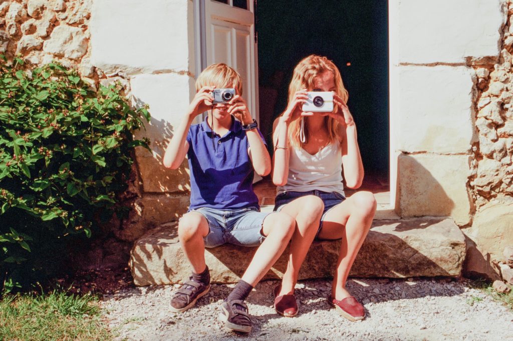 two-kids-pointing-cameras-at-the-photo-taker